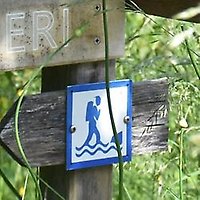 Skylt som visar ett pictogram av en vandrare med vågor av vatten under.